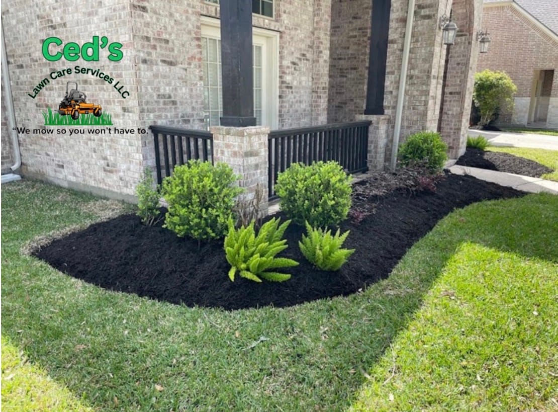 Fresh dark mulch and shrubs around a brick home front entry